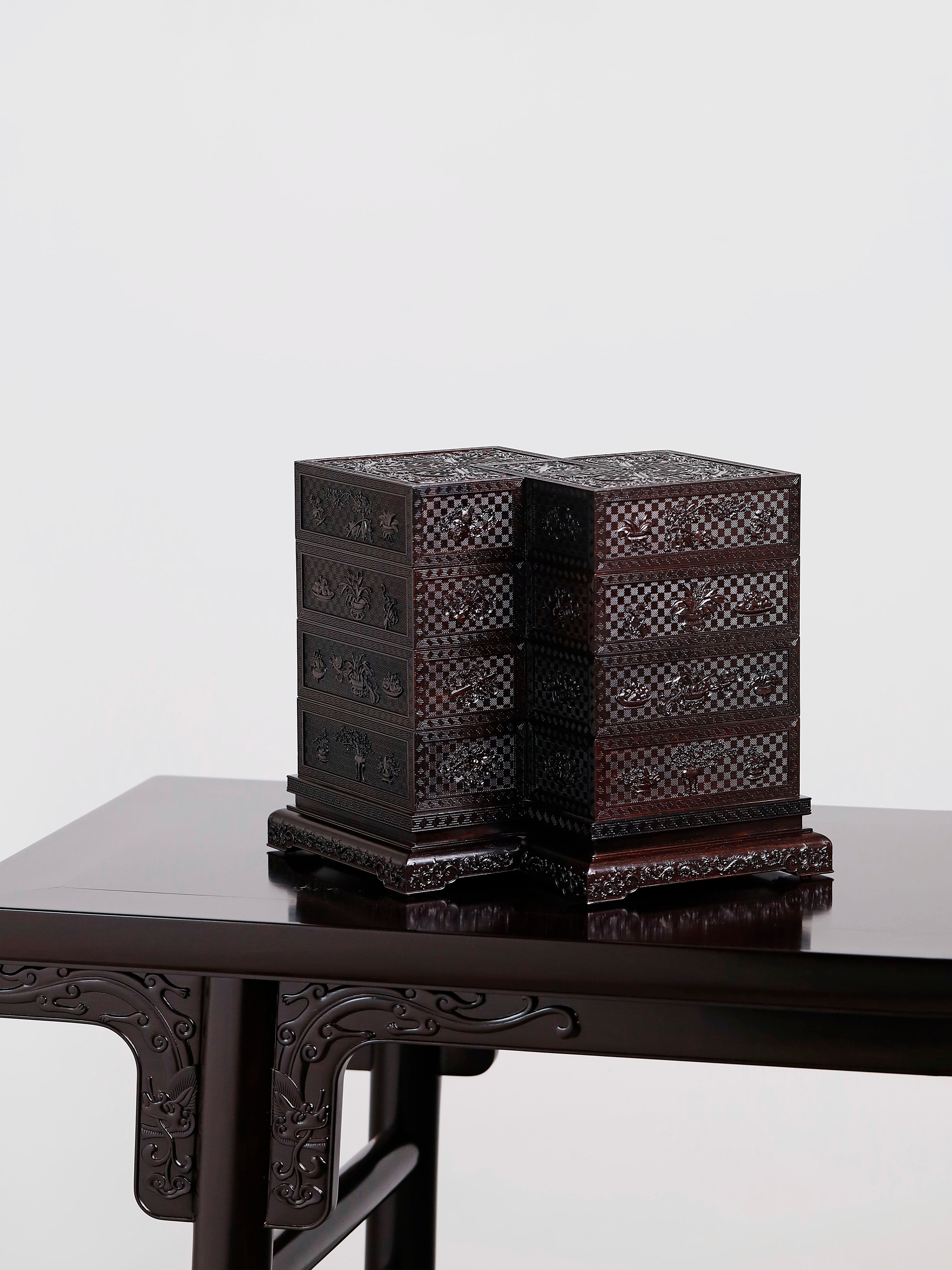 Four-tiered box in the shape of a square knot with full carvings of floral and dragon patterns.