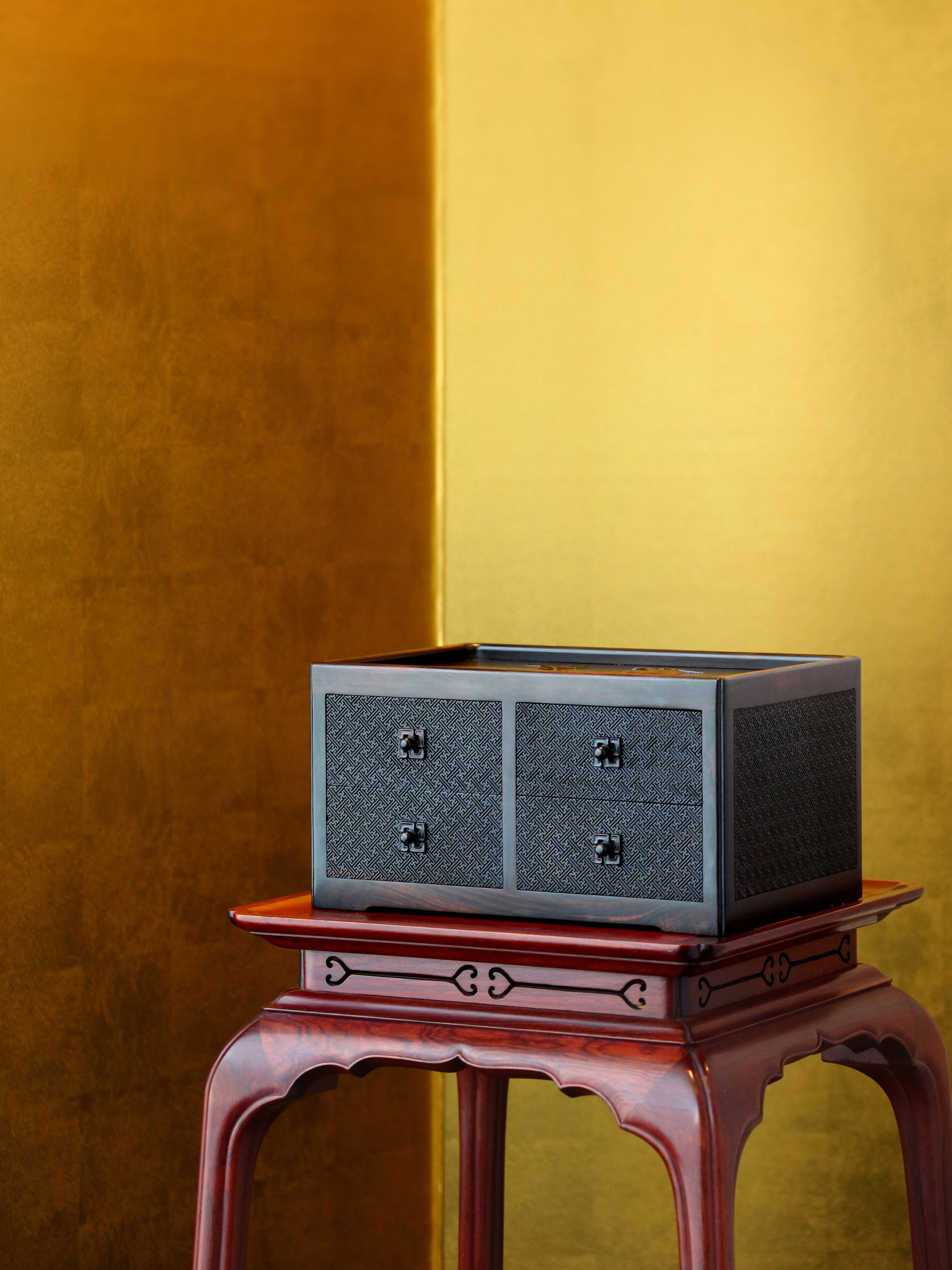 A four-drawer tea box carved from large-leaf sandalwood with silk feathers and hoopoe and swastika patterns.