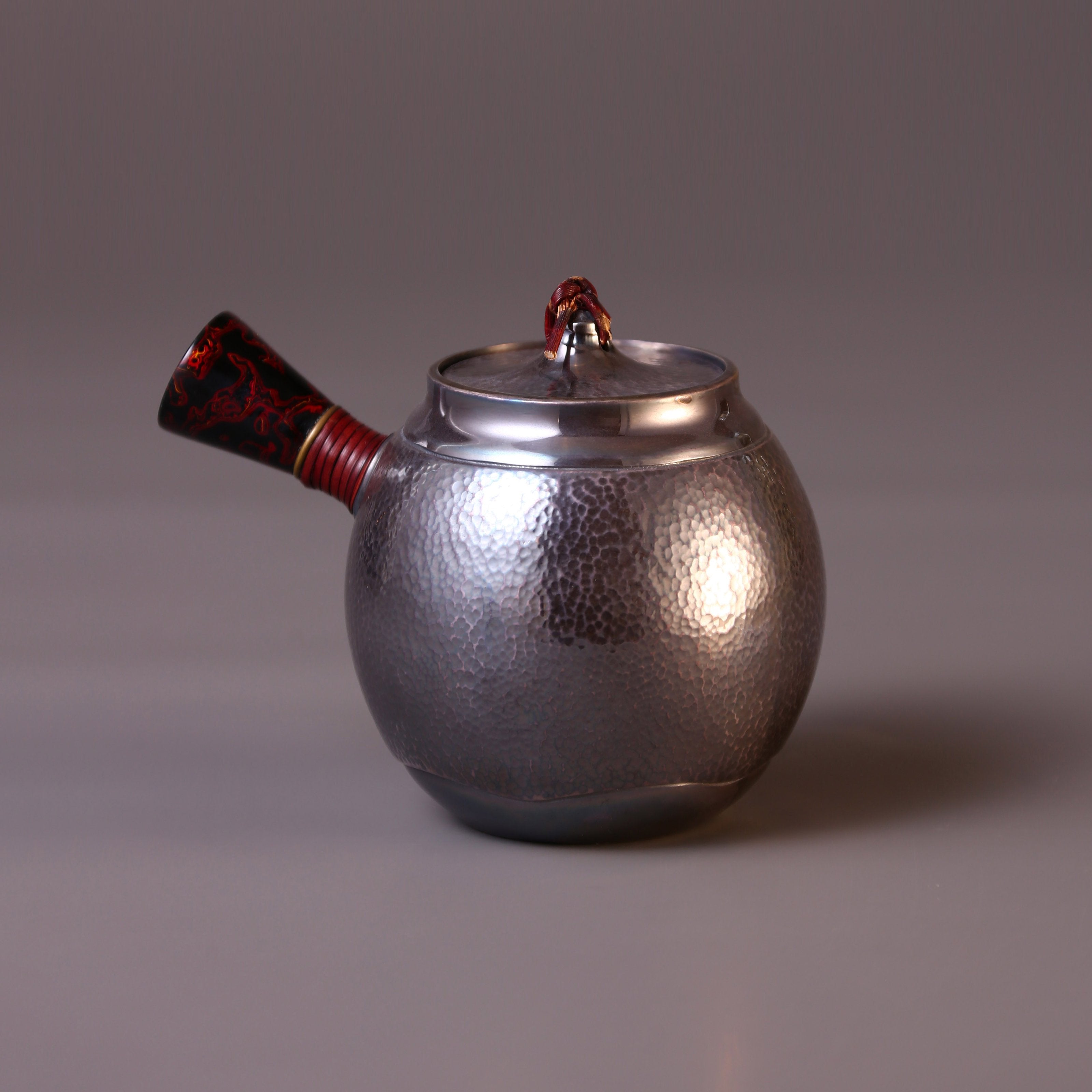 Hong Jike, an inheritor of the intangible cultural heritage, makes a lacquered, side-handled, pure silver teapot.
