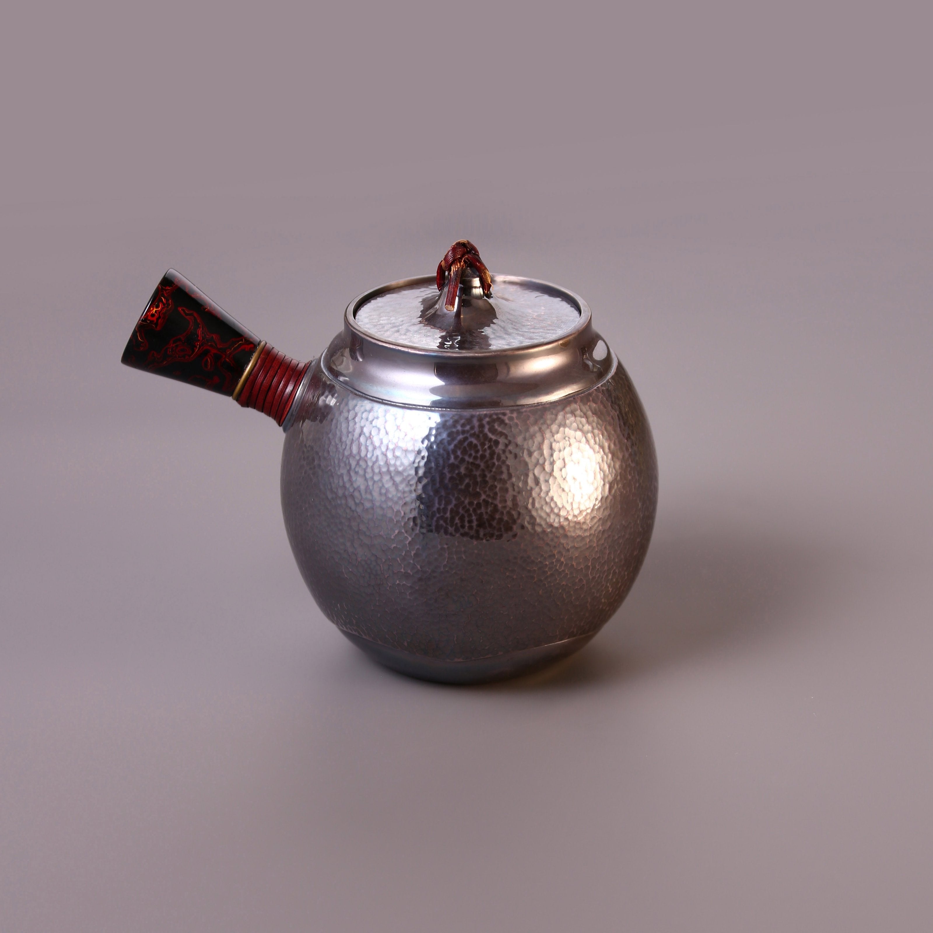 Hong Jike, an inheritor of the intangible cultural heritage, makes a lacquered, side-handled, pure silver teapot.
