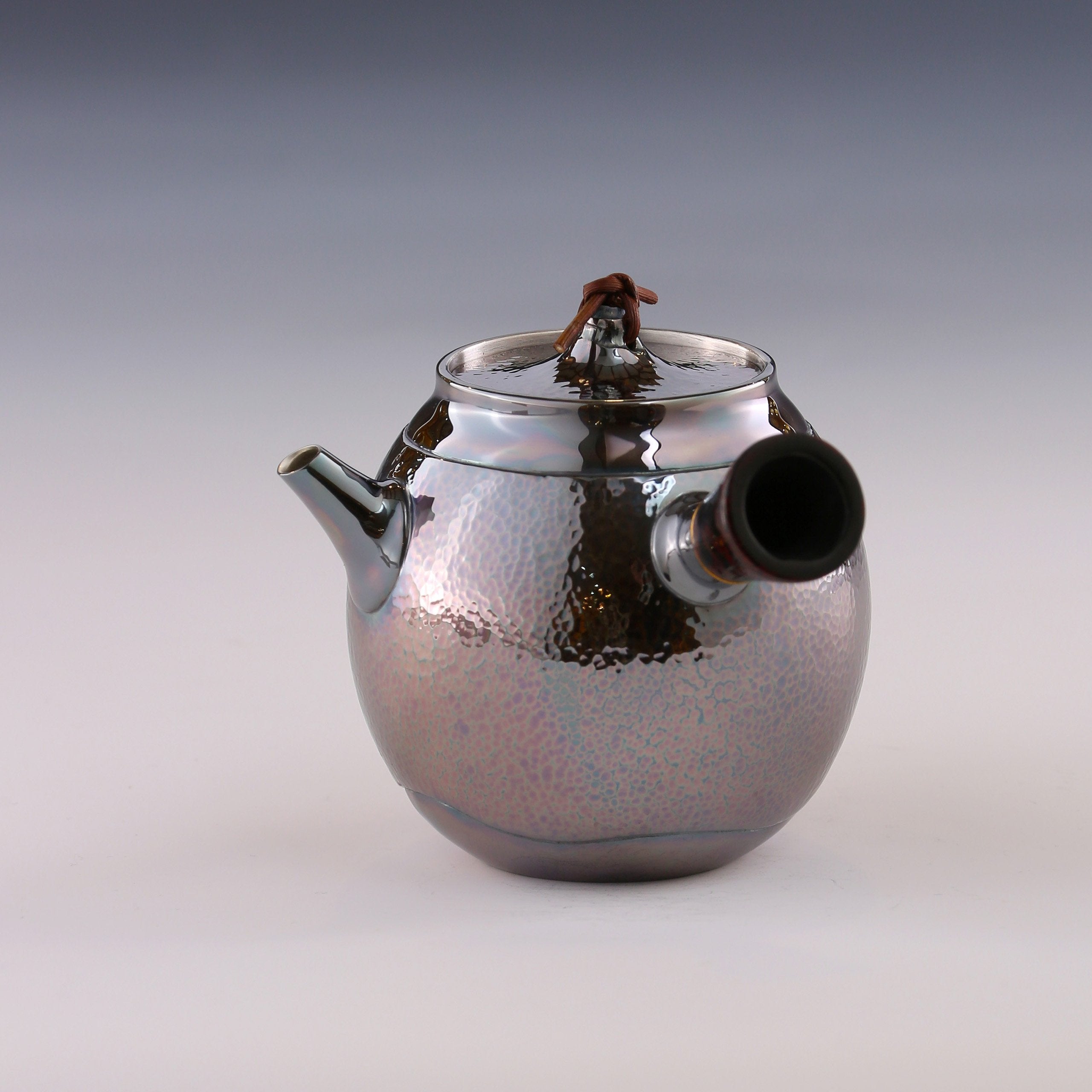 Hong Jike, an inheritor of the intangible cultural heritage, makes a lacquered, side-handled, pure silver teapot.