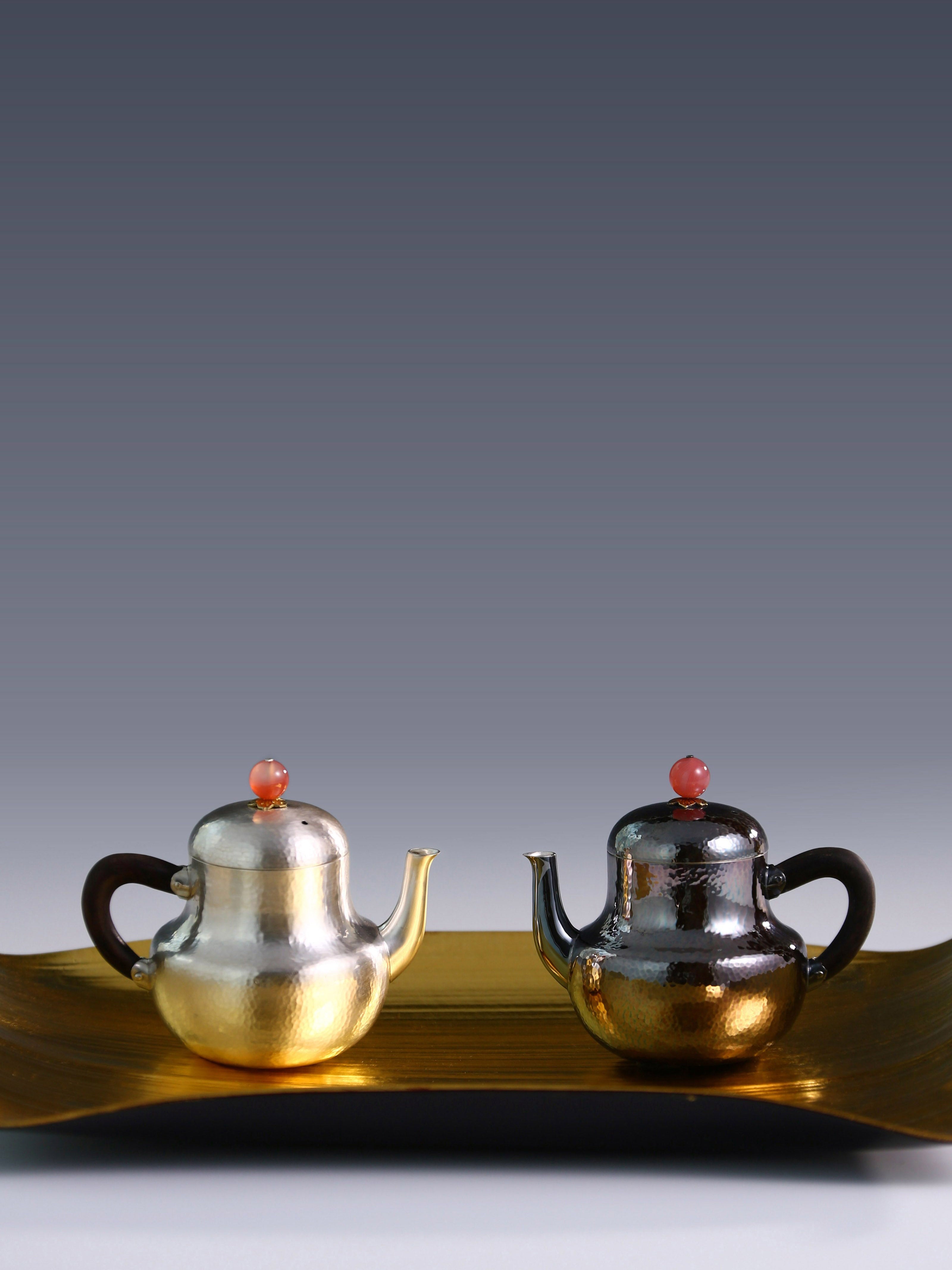 A pair of red-topped Siting sterling silver teapots