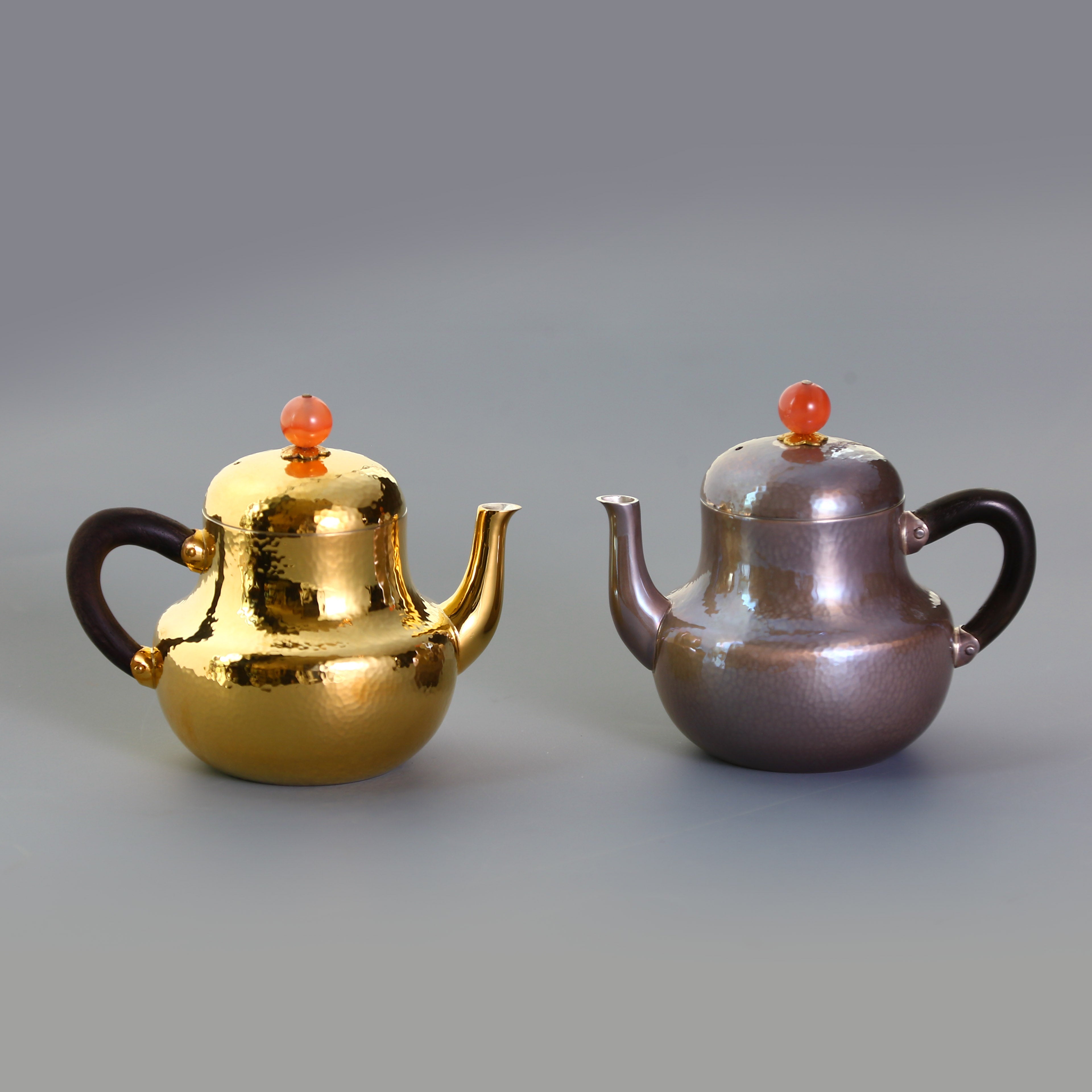 A pair of red-topped Siting sterling silver teapots