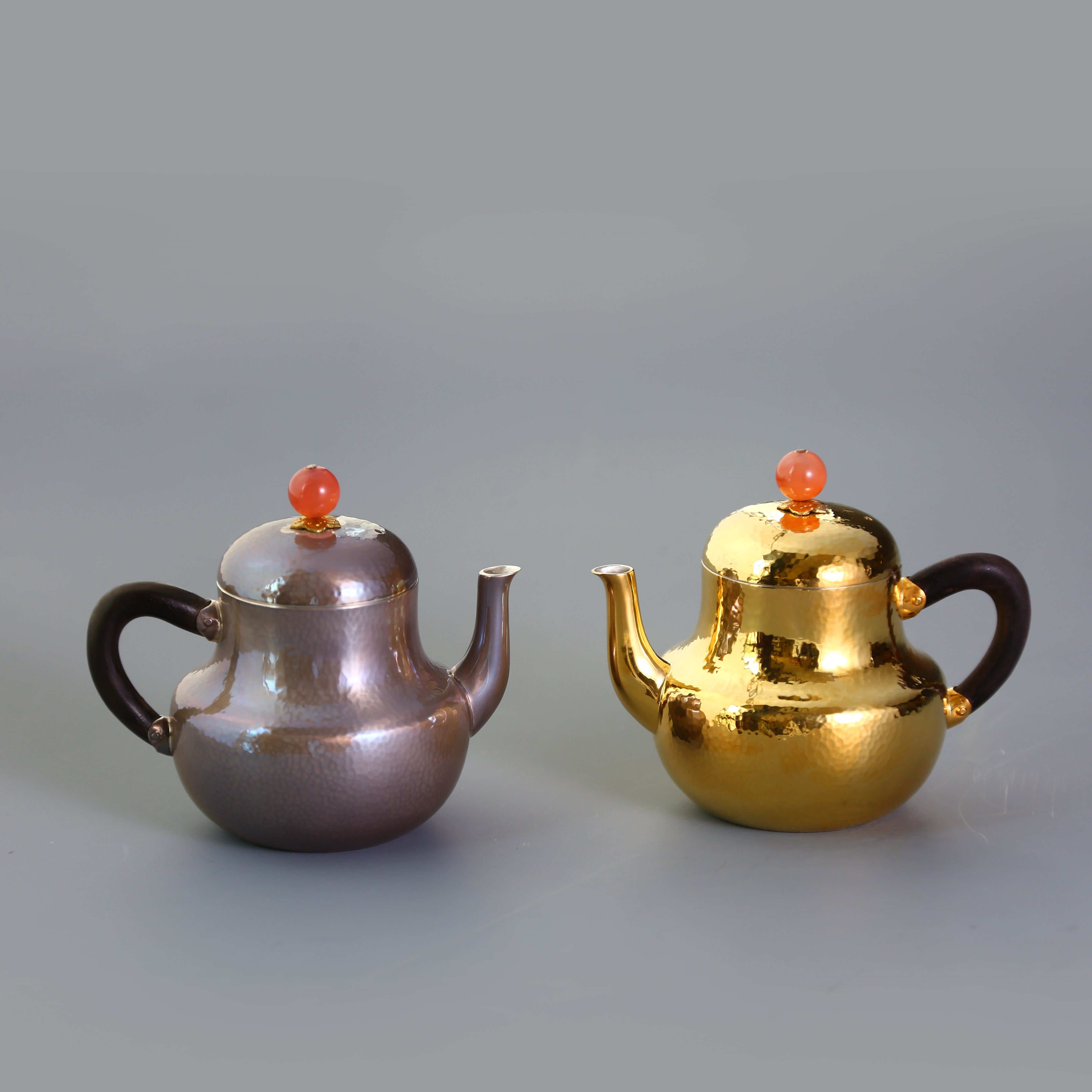 A pair of red-topped Siting sterling silver teapots