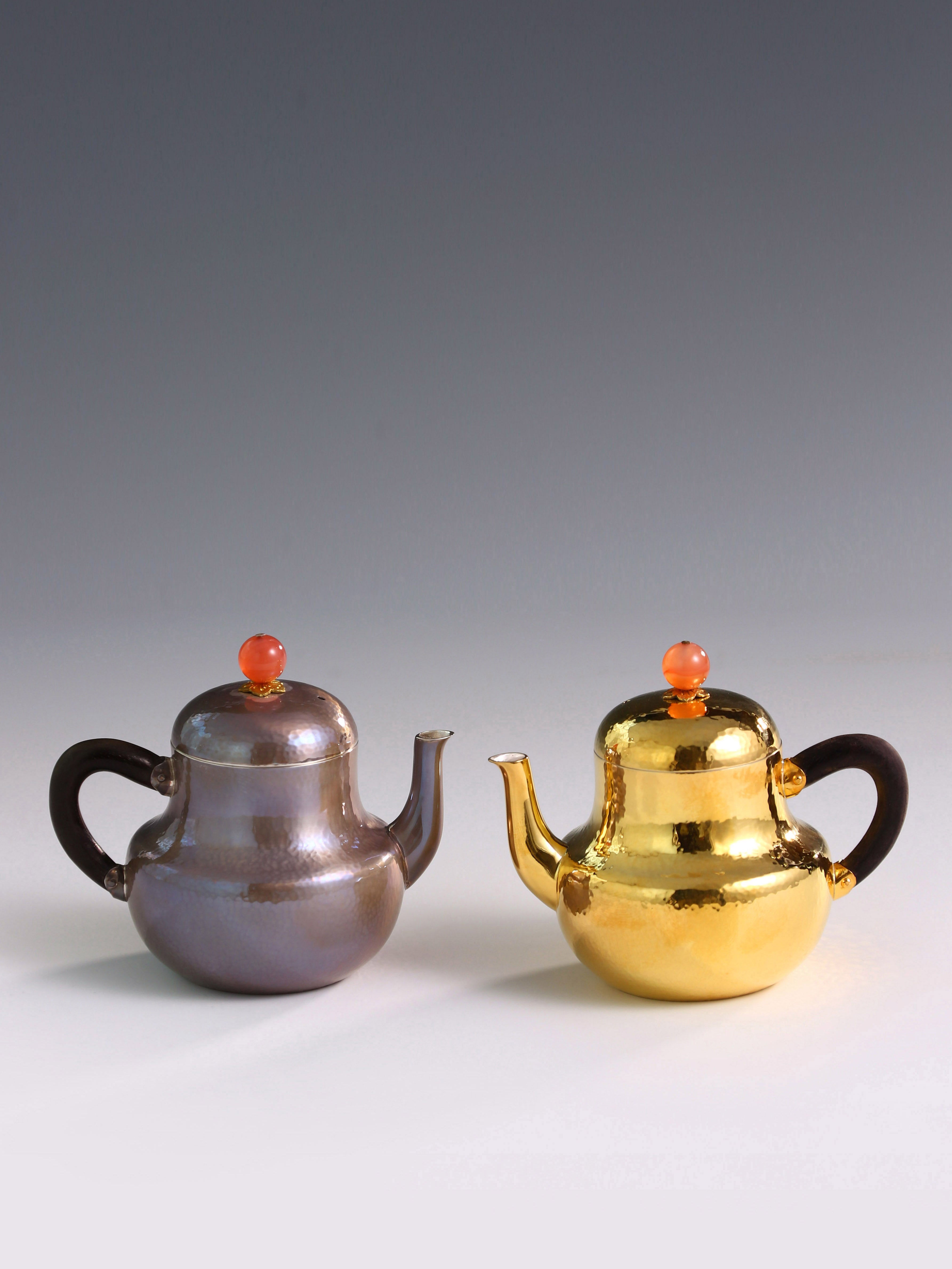 A pair of red-topped Siting sterling silver teapots