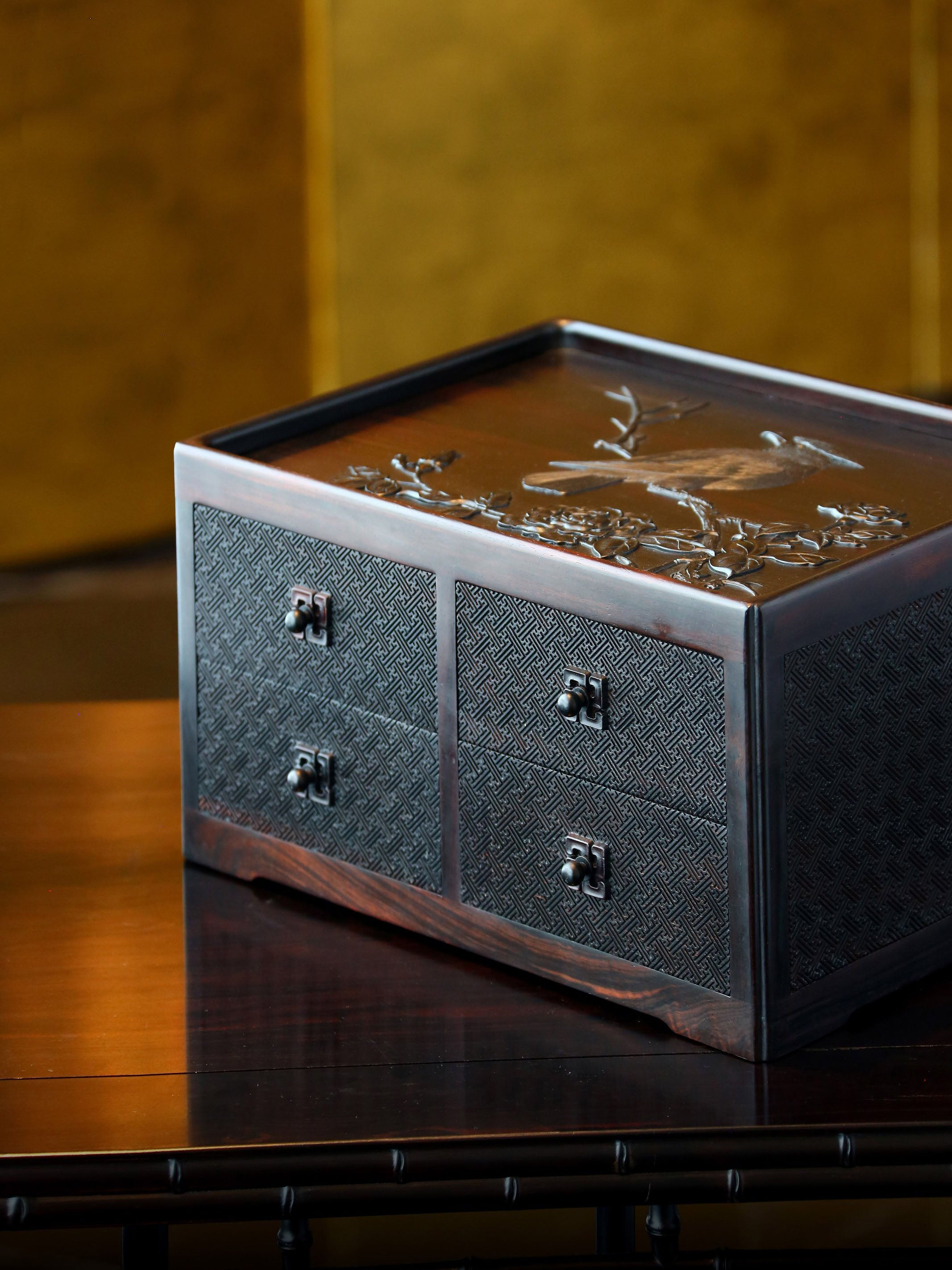 A four-drawer tea box carved from large-leaf sandalwood with silk feathers and hoopoe and swastika patterns.