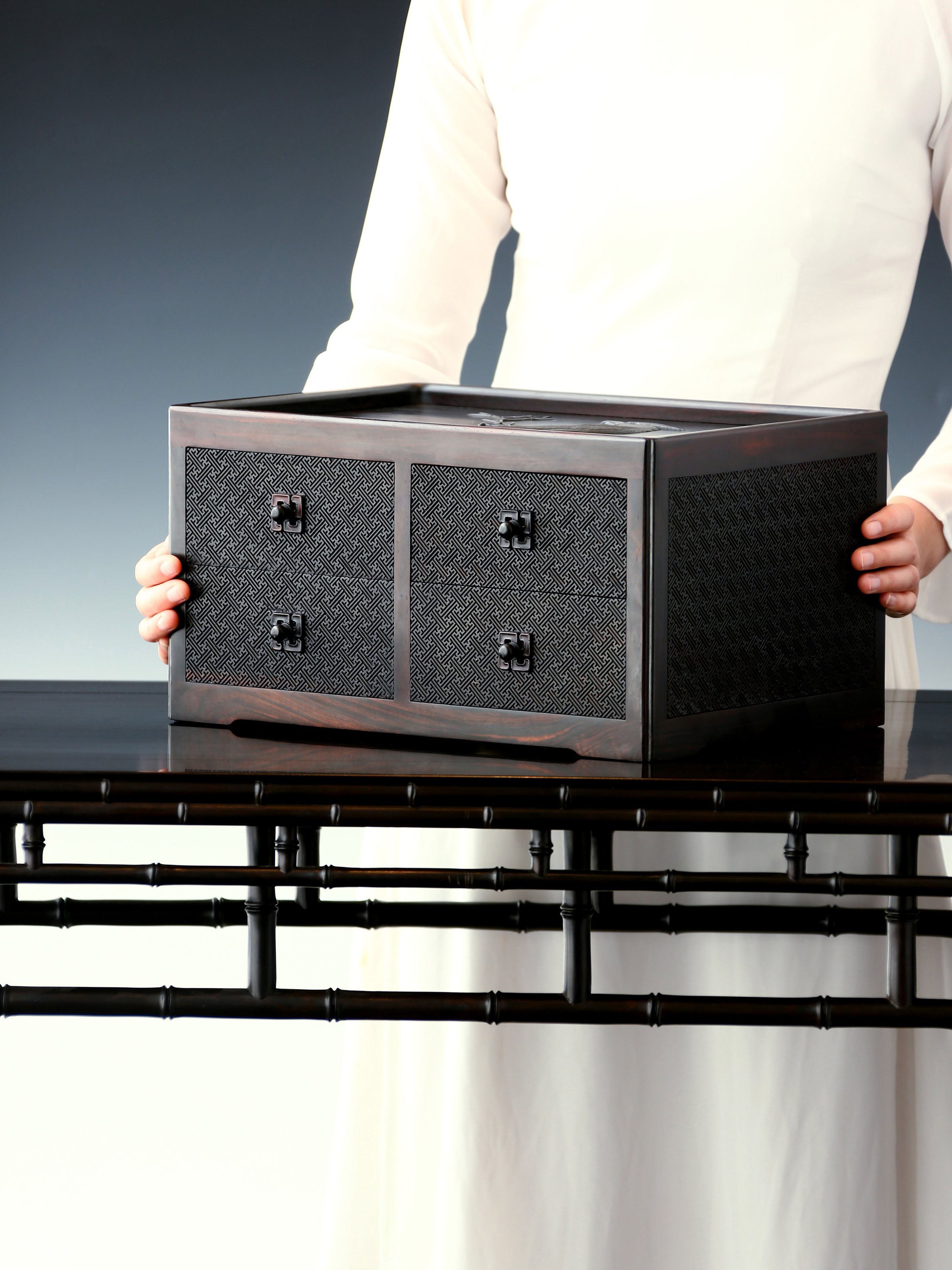 A four-drawer tea box carved from large-leaf sandalwood with silk feathers and hoopoe and swastika patterns.