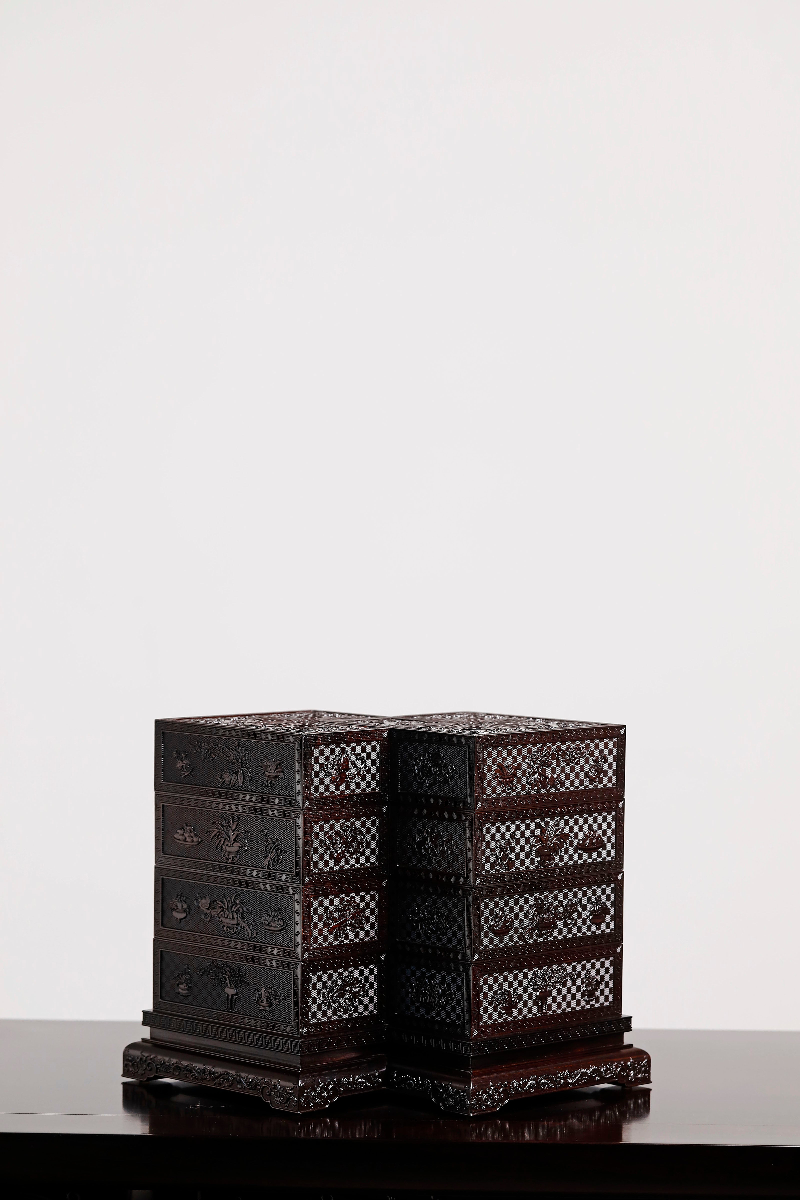Four-tiered box in the shape of a square knot with full carvings of floral and dragon patterns.