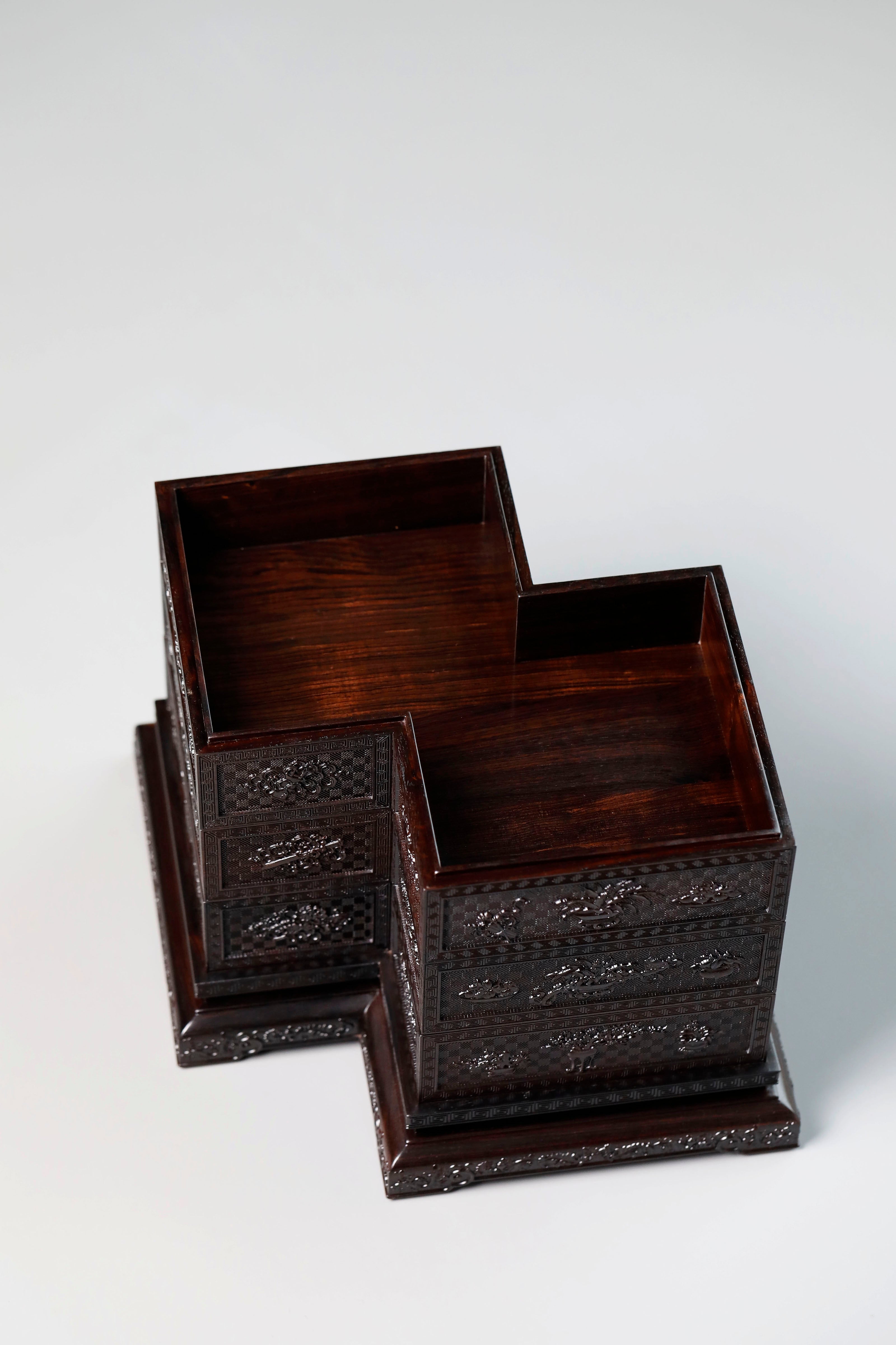Four-tiered box in the shape of a square knot with full carvings of floral and dragon patterns.