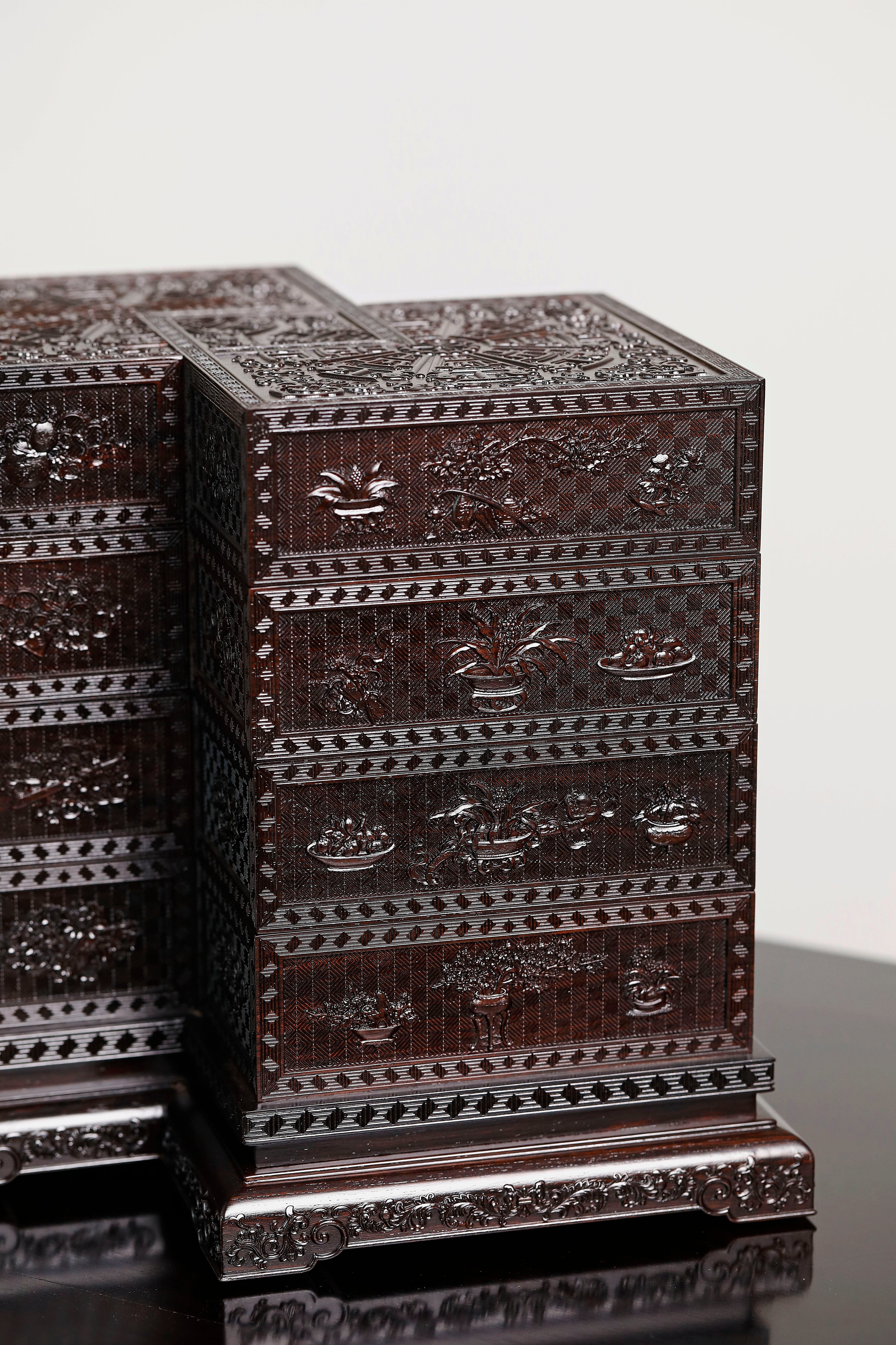 Four-tiered box in the shape of a square knot with full carvings of floral and dragon patterns.