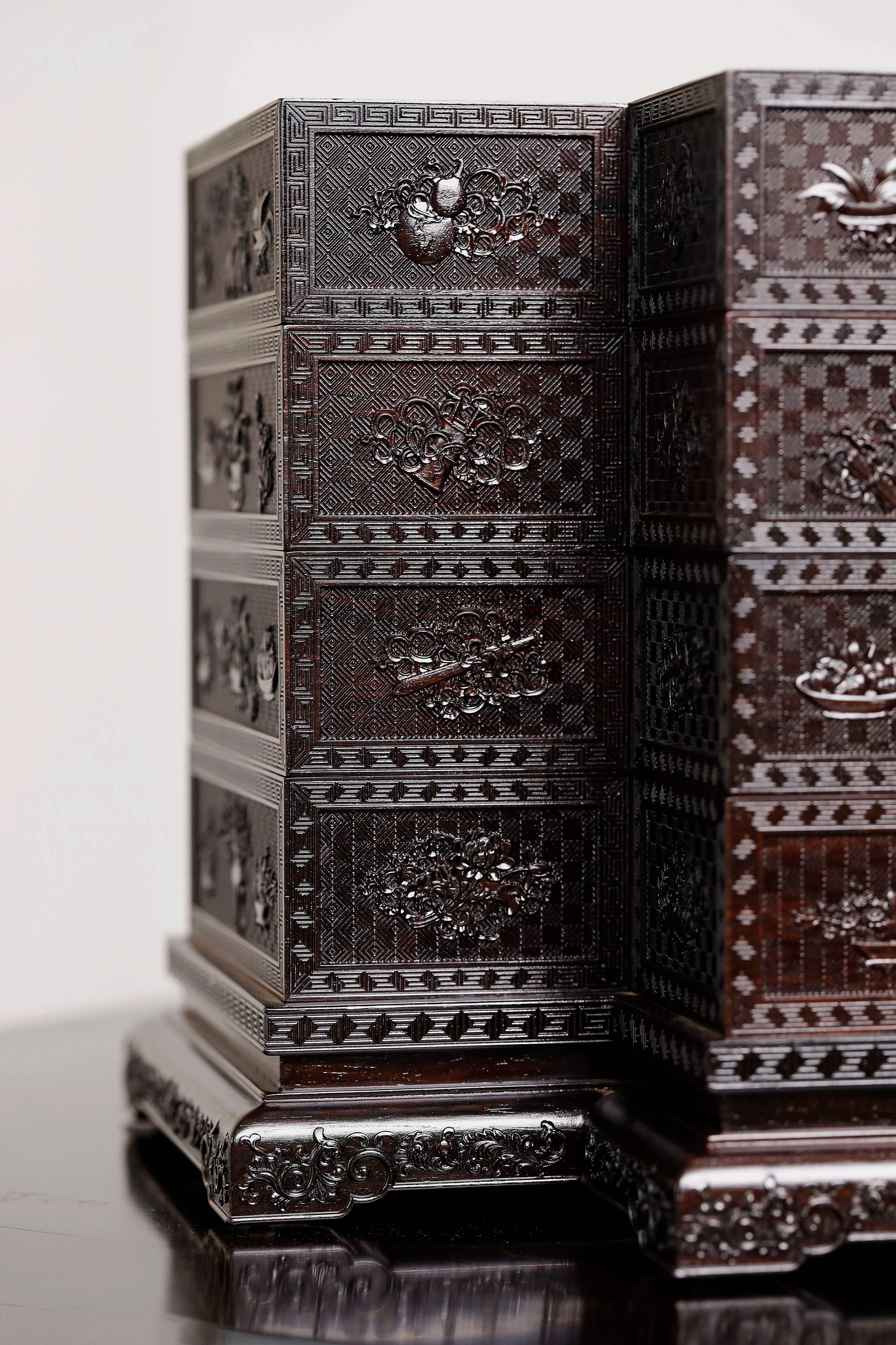 Four-tiered box in the shape of a square knot with full carvings of floral and dragon patterns.