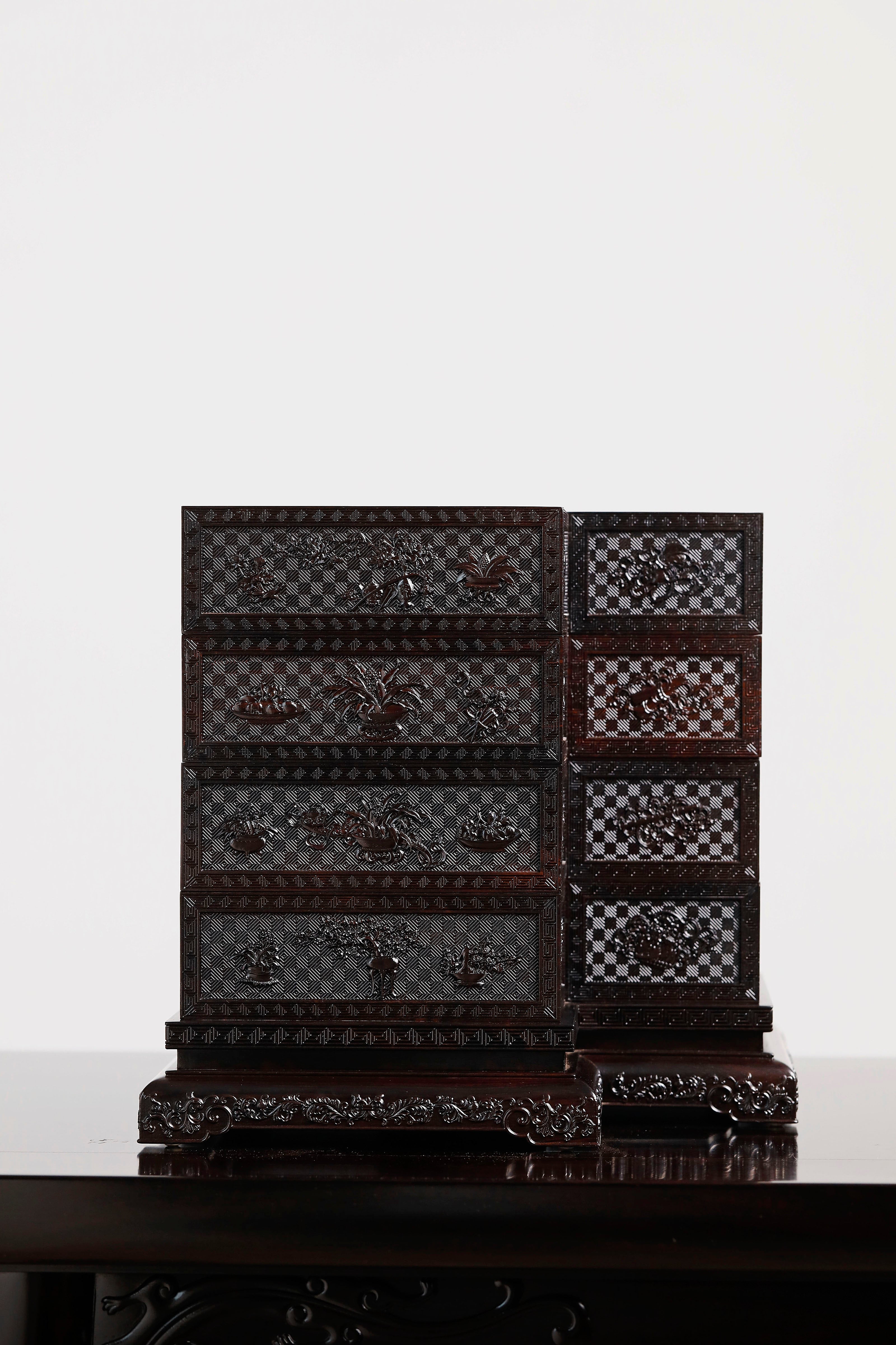 Four-tiered box in the shape of a square knot with full carvings of floral and dragon patterns.