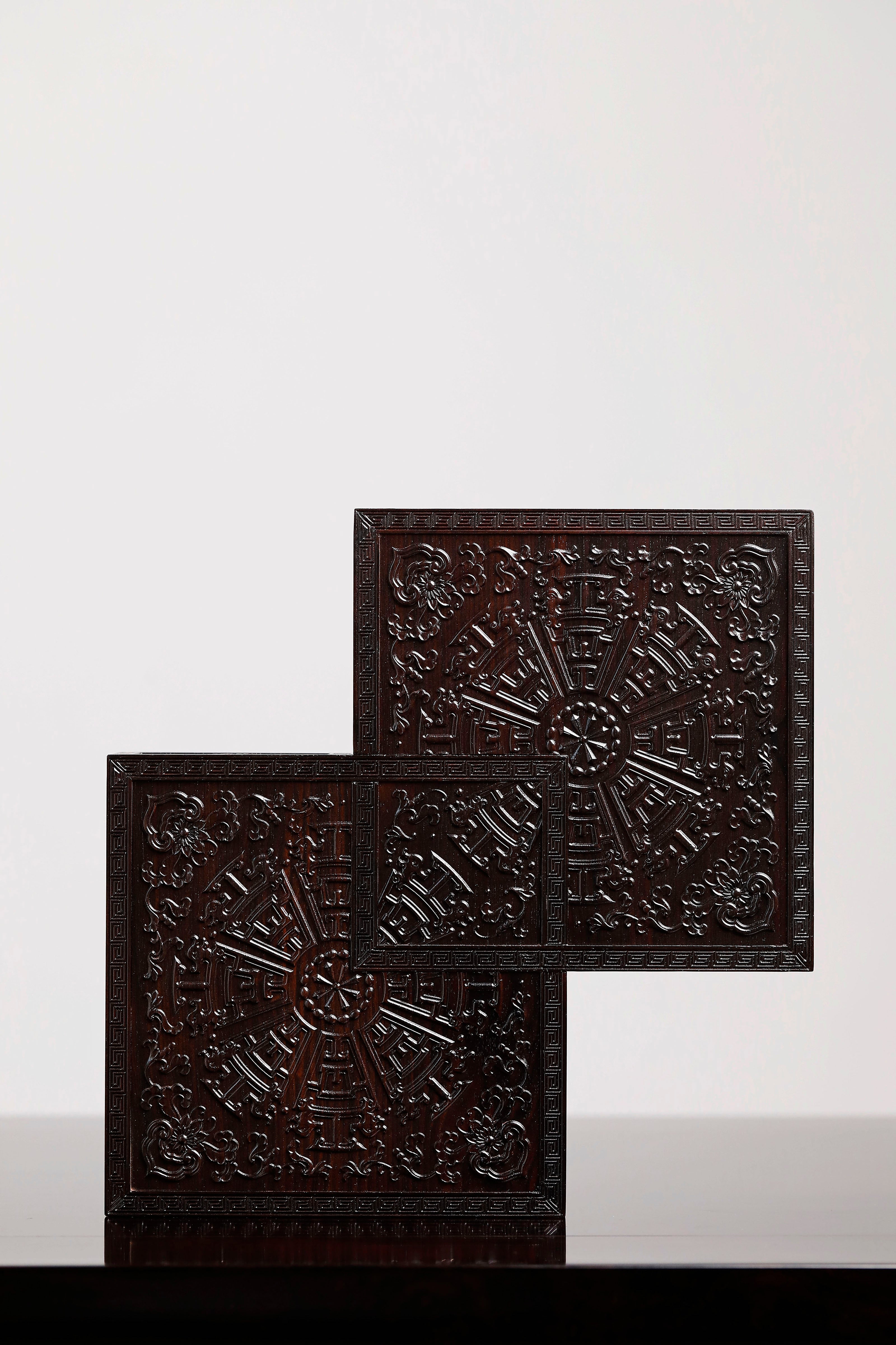 Four-tiered box in the shape of a square knot with full carvings of floral and dragon patterns.