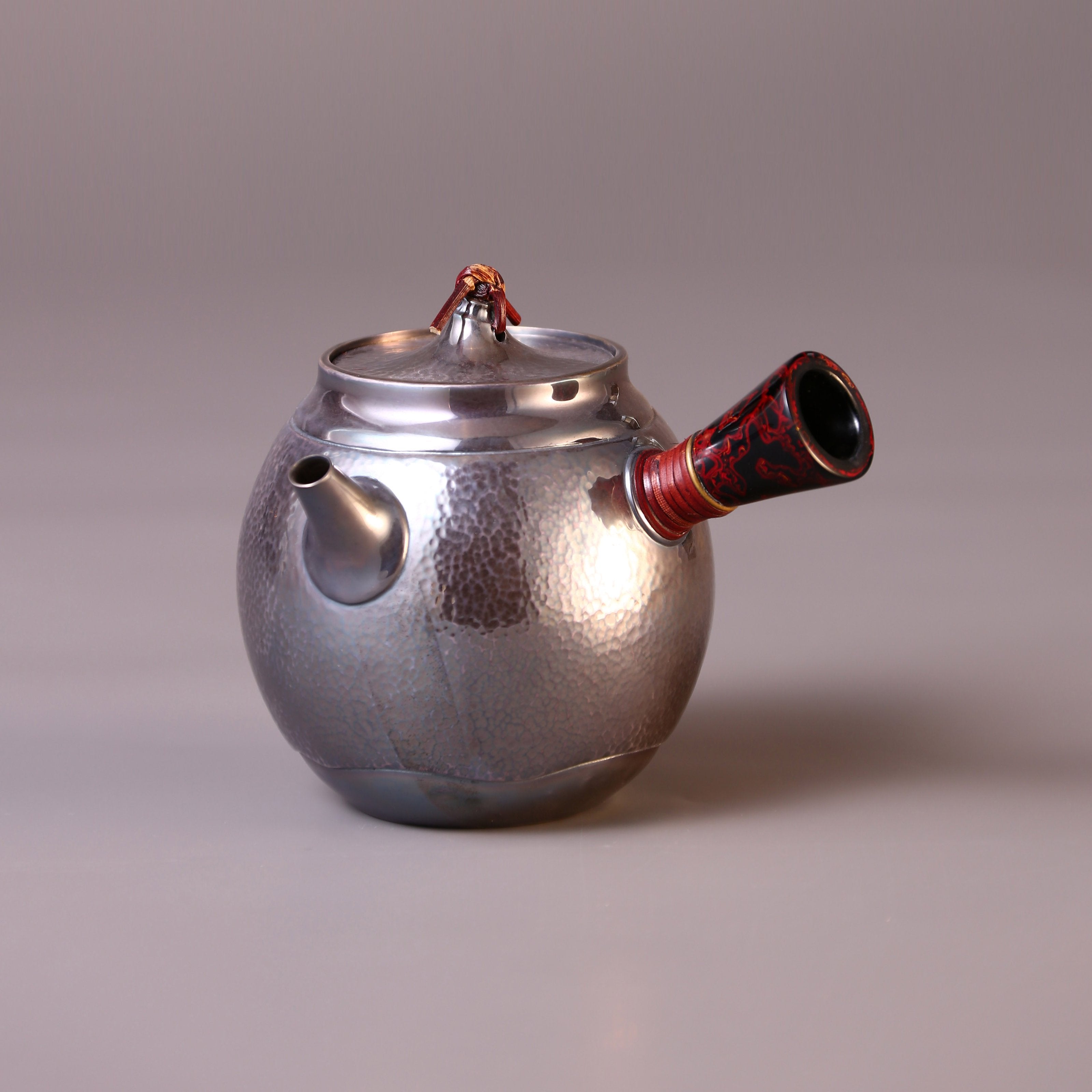 Hong Jike, an inheritor of the intangible cultural heritage, makes a lacquered, side-handled, pure silver teapot.