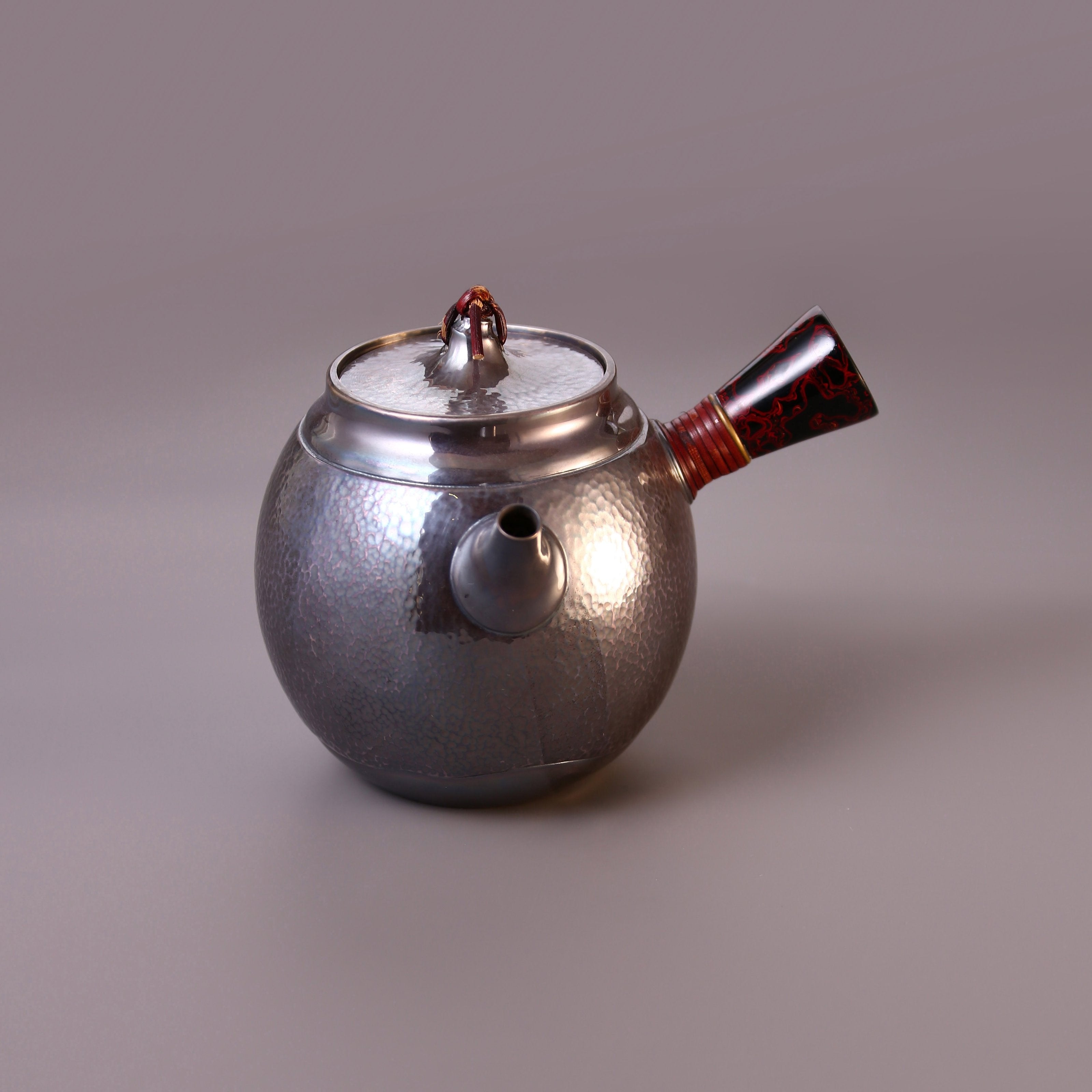 Hong Jike, an inheritor of the intangible cultural heritage, makes a lacquered, side-handled, pure silver teapot.