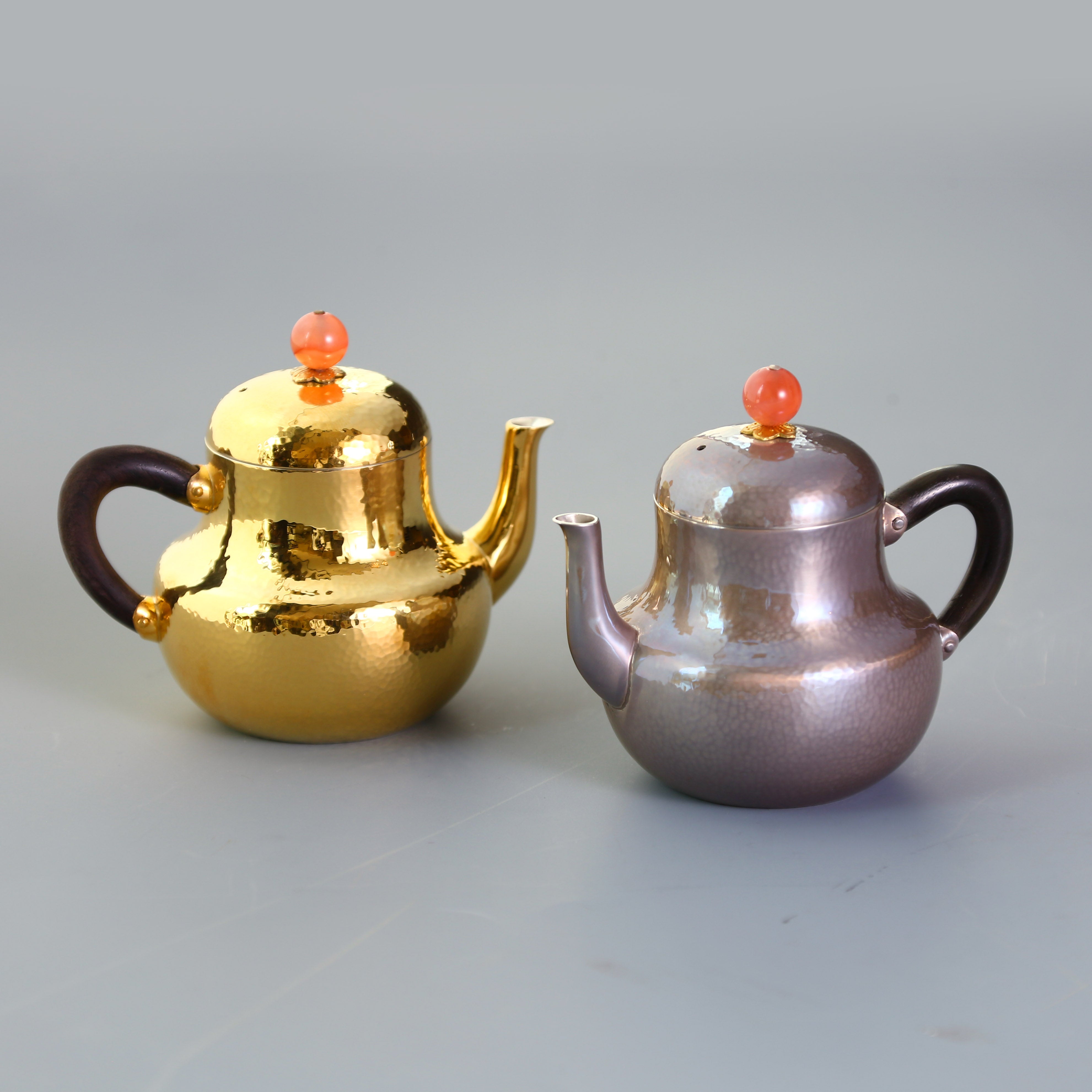 A pair of red-topped Siting sterling silver teapots