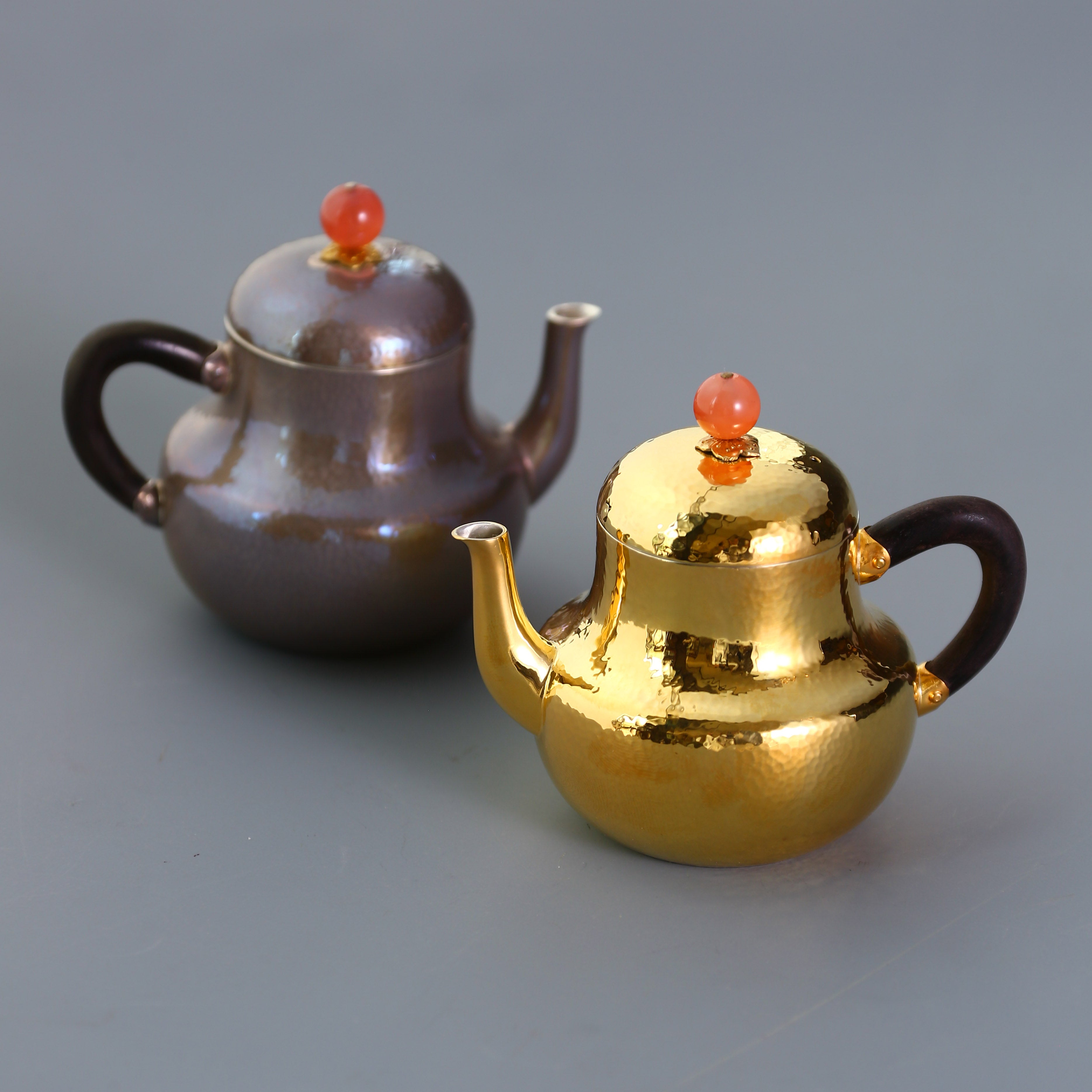 A pair of red-topped Siting sterling silver teapots