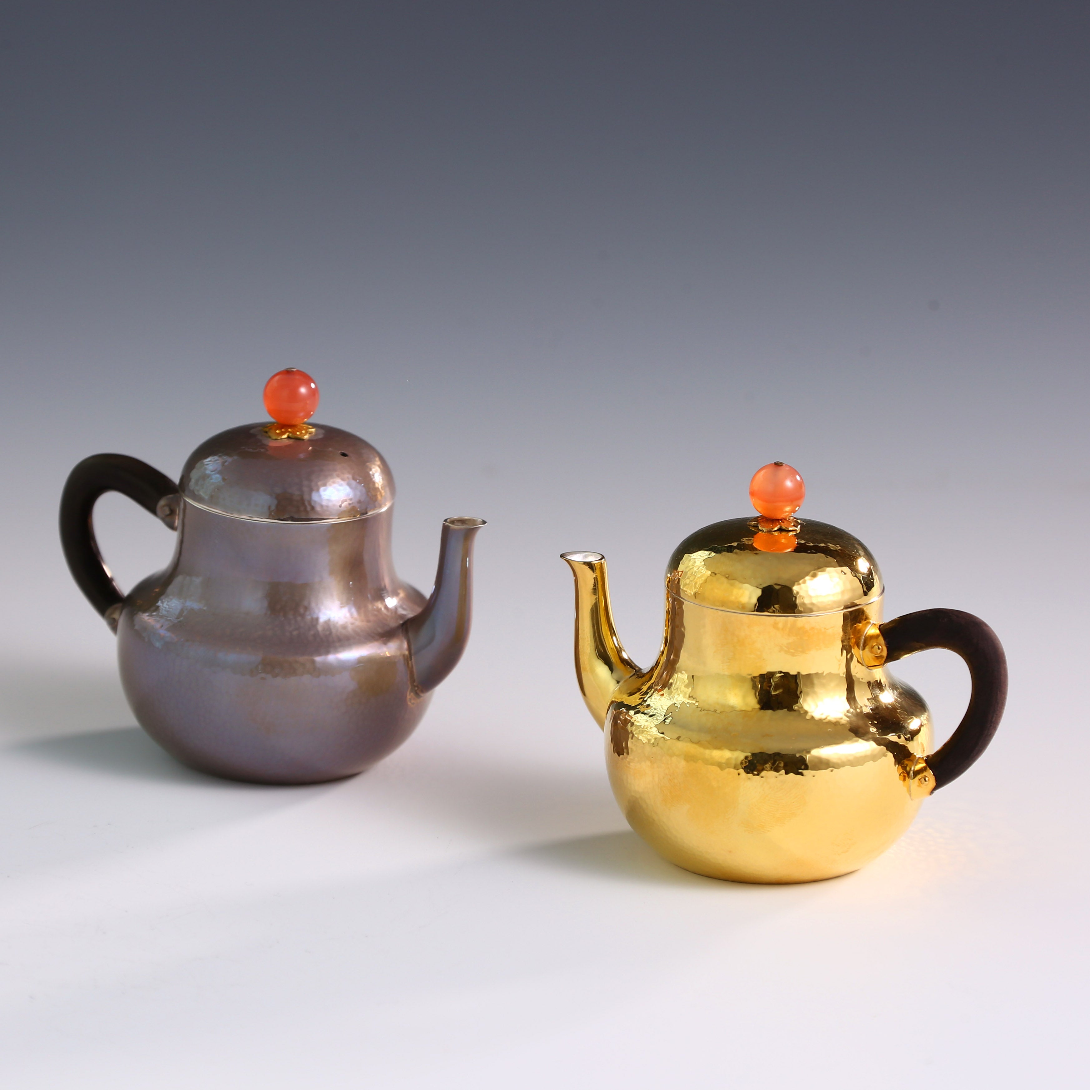 A pair of red-topped Siting sterling silver teapots