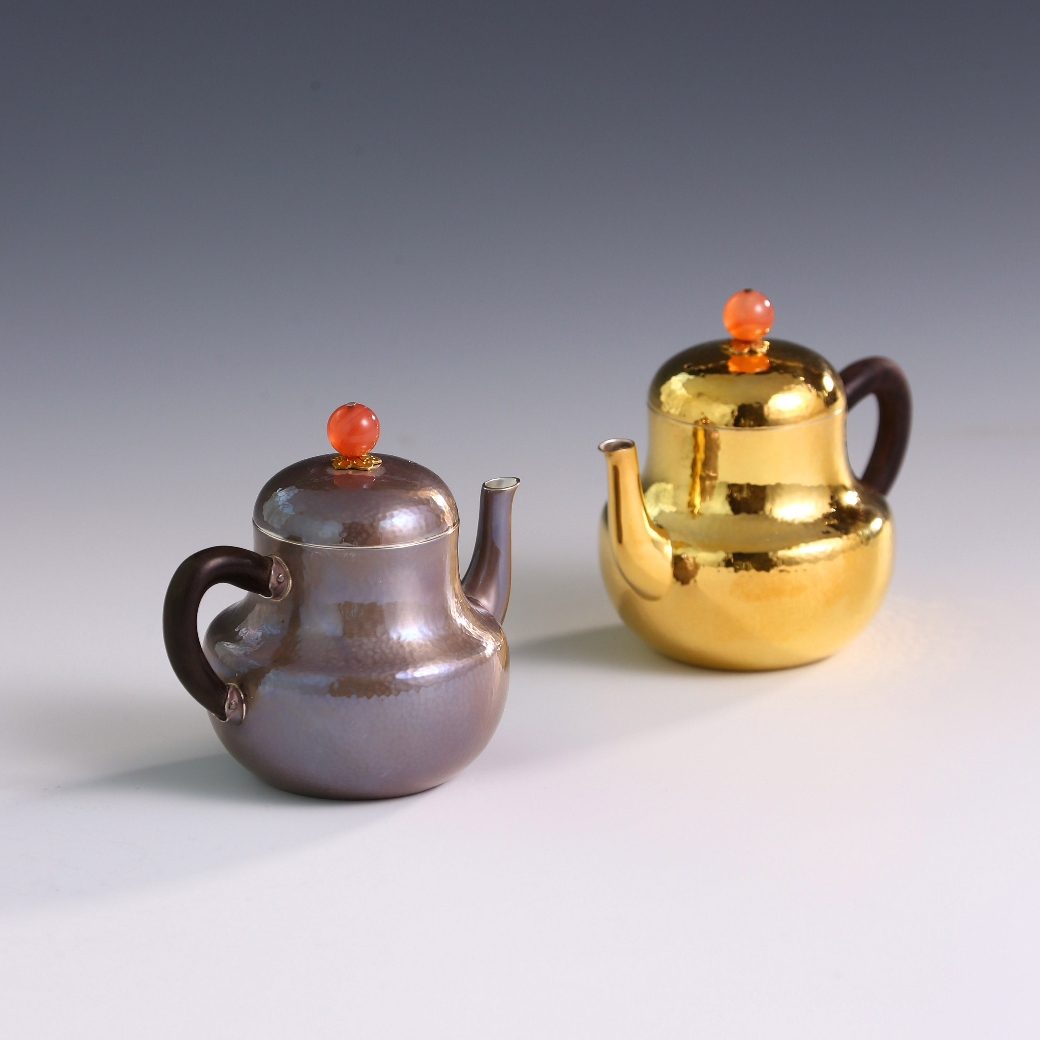 A pair of red-topped Siting sterling silver teapots