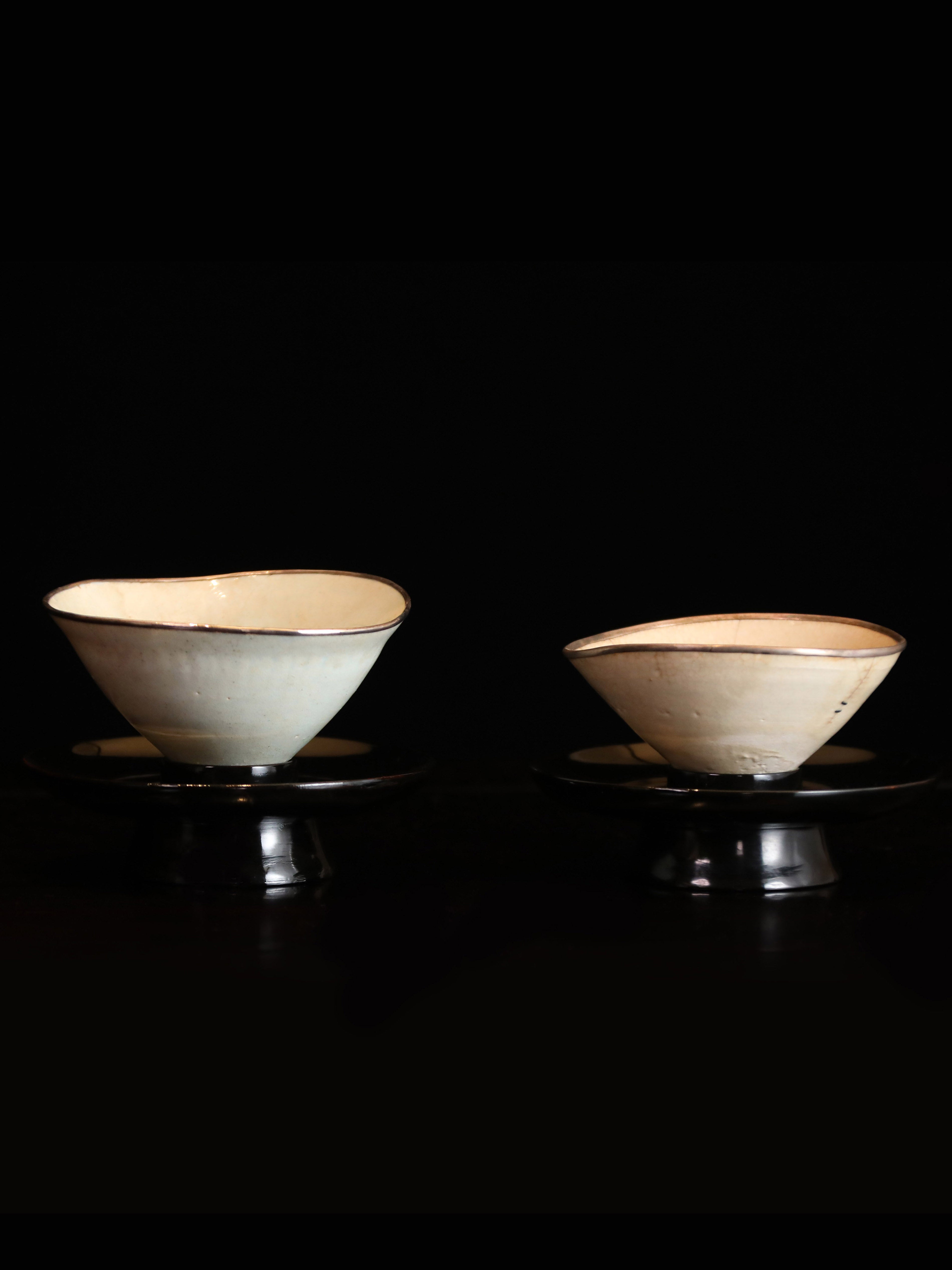 A pair of mended porcelain bowls from the Hutian kiln (with lacquered saucers)