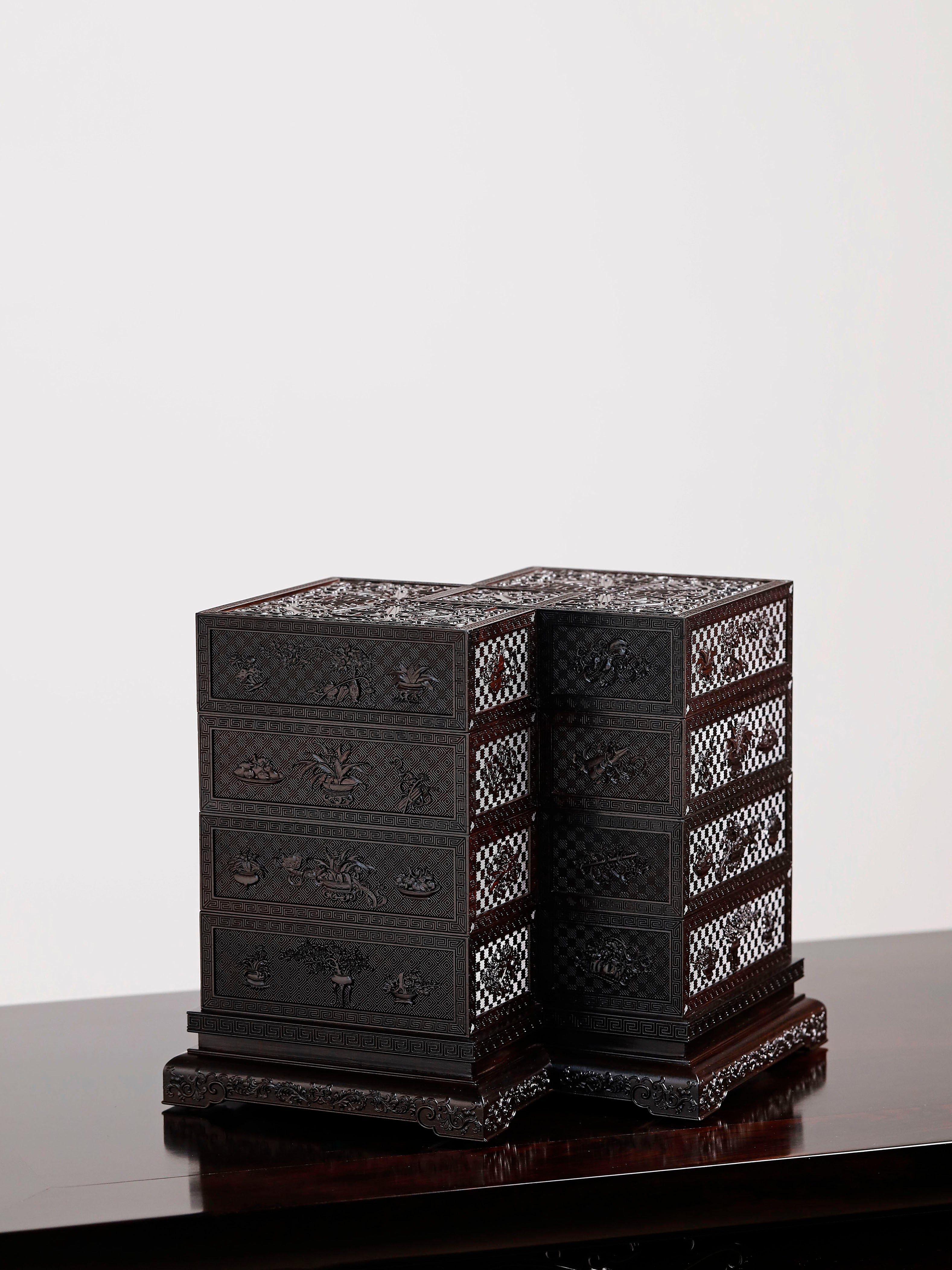Four-tiered box in the shape of a square knot with full carvings of floral and dragon patterns.