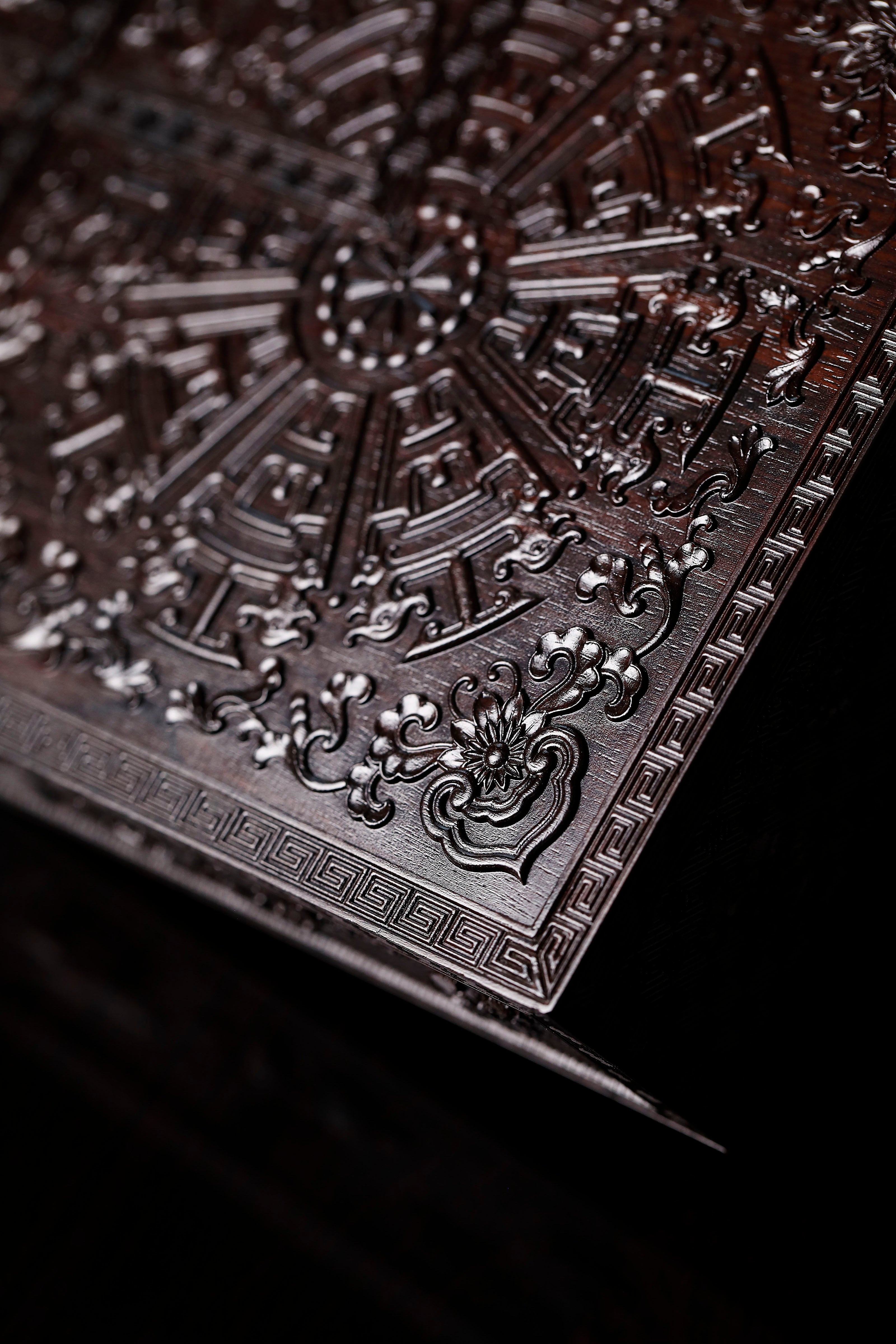 Four-tiered box in the shape of a square knot with full carvings of floral and dragon patterns.