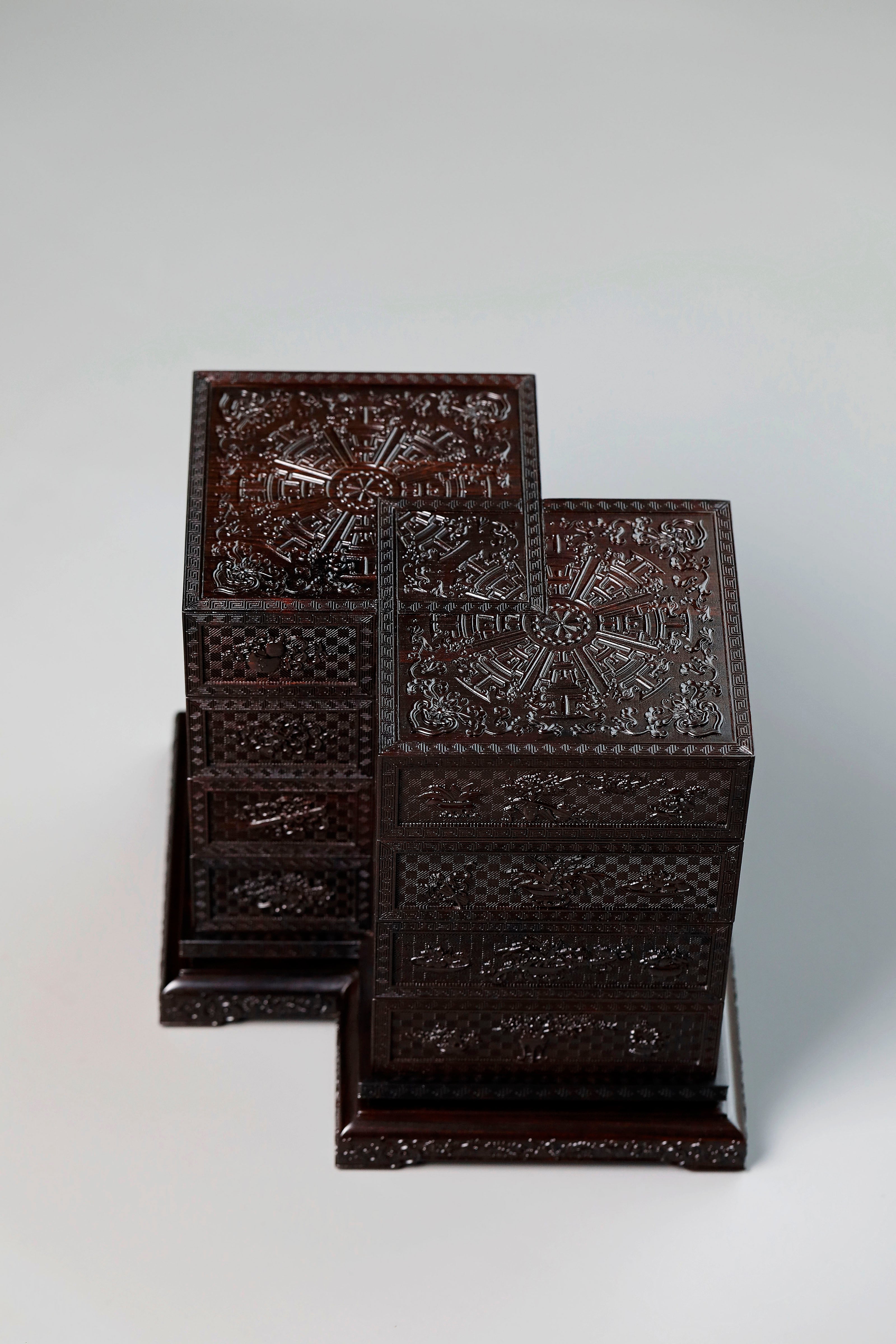 Four-tiered box in the shape of a square knot with full carvings of floral and dragon patterns.