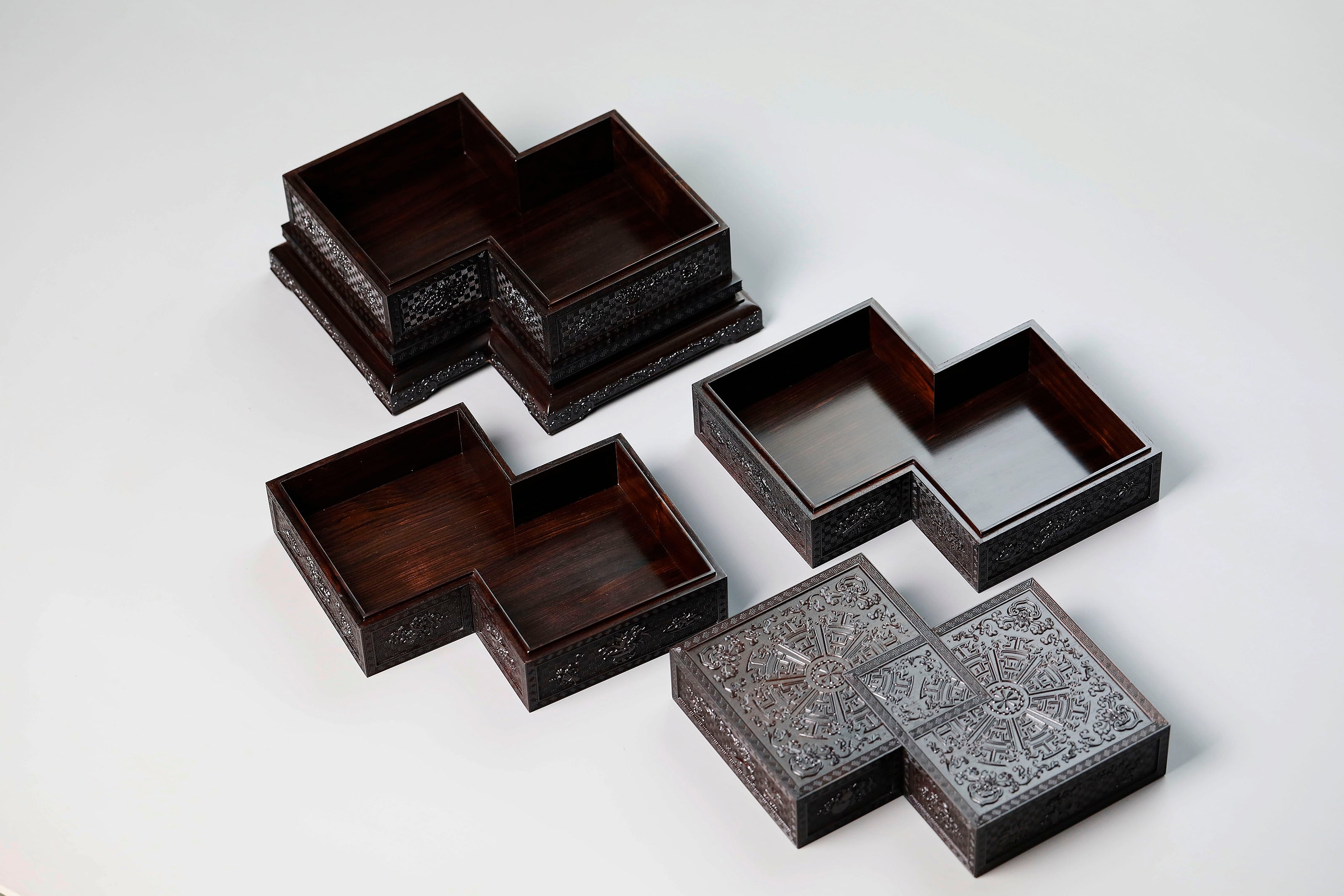 Four-tiered box in the shape of a square knot with full carvings of floral and dragon patterns.