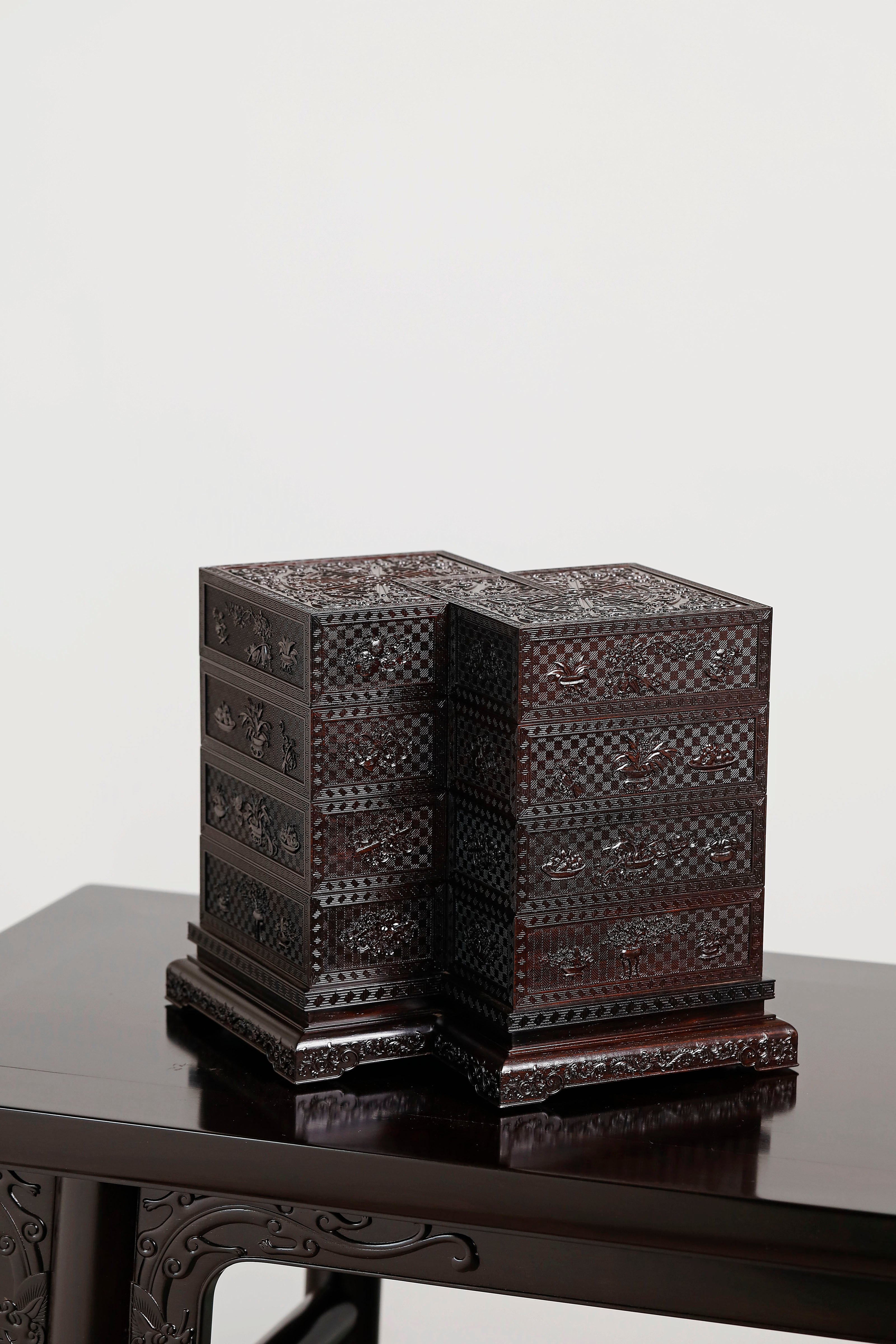 Four-tiered box in the shape of a square knot with full carvings of floral and dragon patterns.